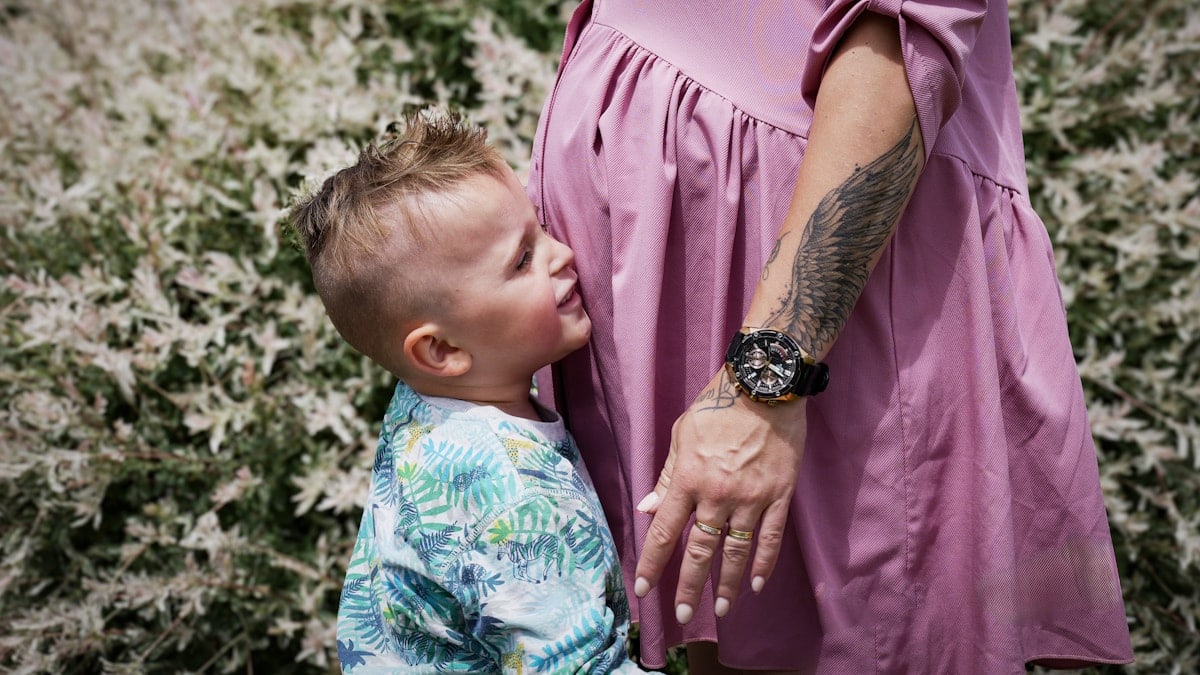 Young child looking at a pregnant woman's belly.